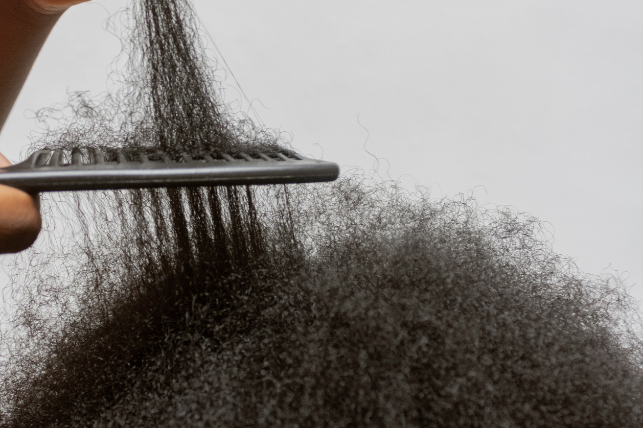 Uneven natural hair strands showing breakage during detangling with a comb