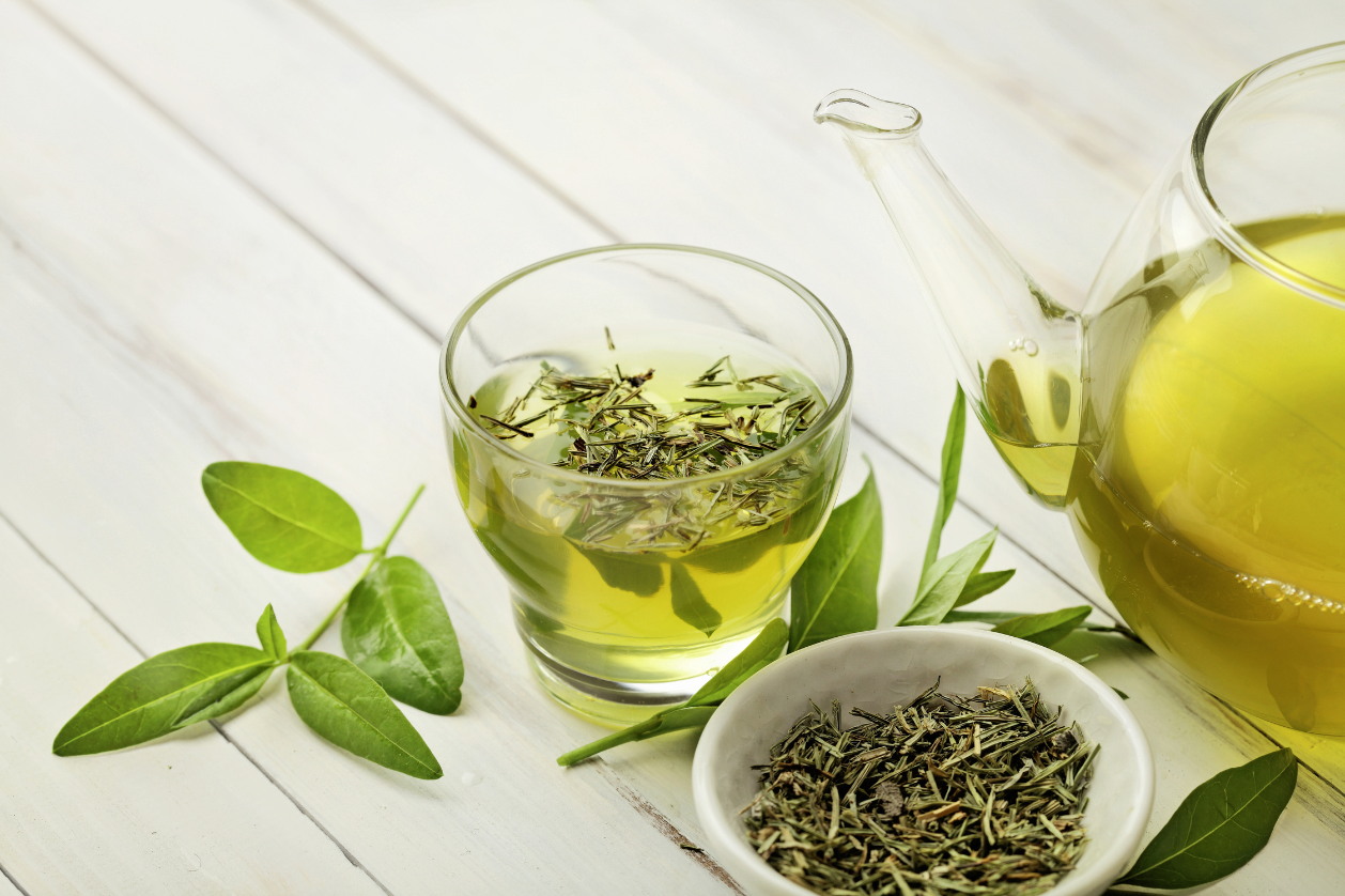 Freshly brewed green tea with loose leaves on a white table — a natural ingredient rich in antioxidants for healthy hair and scalp.